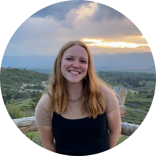 Alicia smiling in-front of a sunset over the mountains